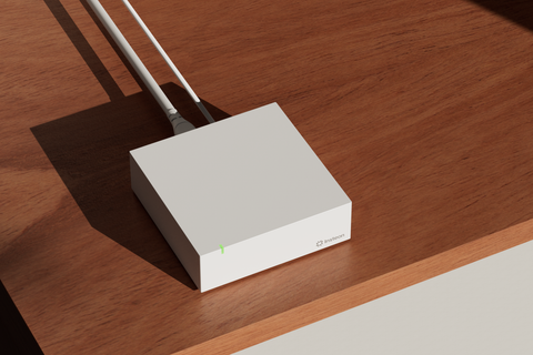 The white Insteon Hub on a wood surface with logo visible
