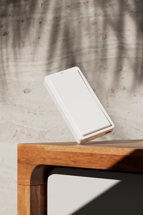 White mini remote balancing on a wooden desk